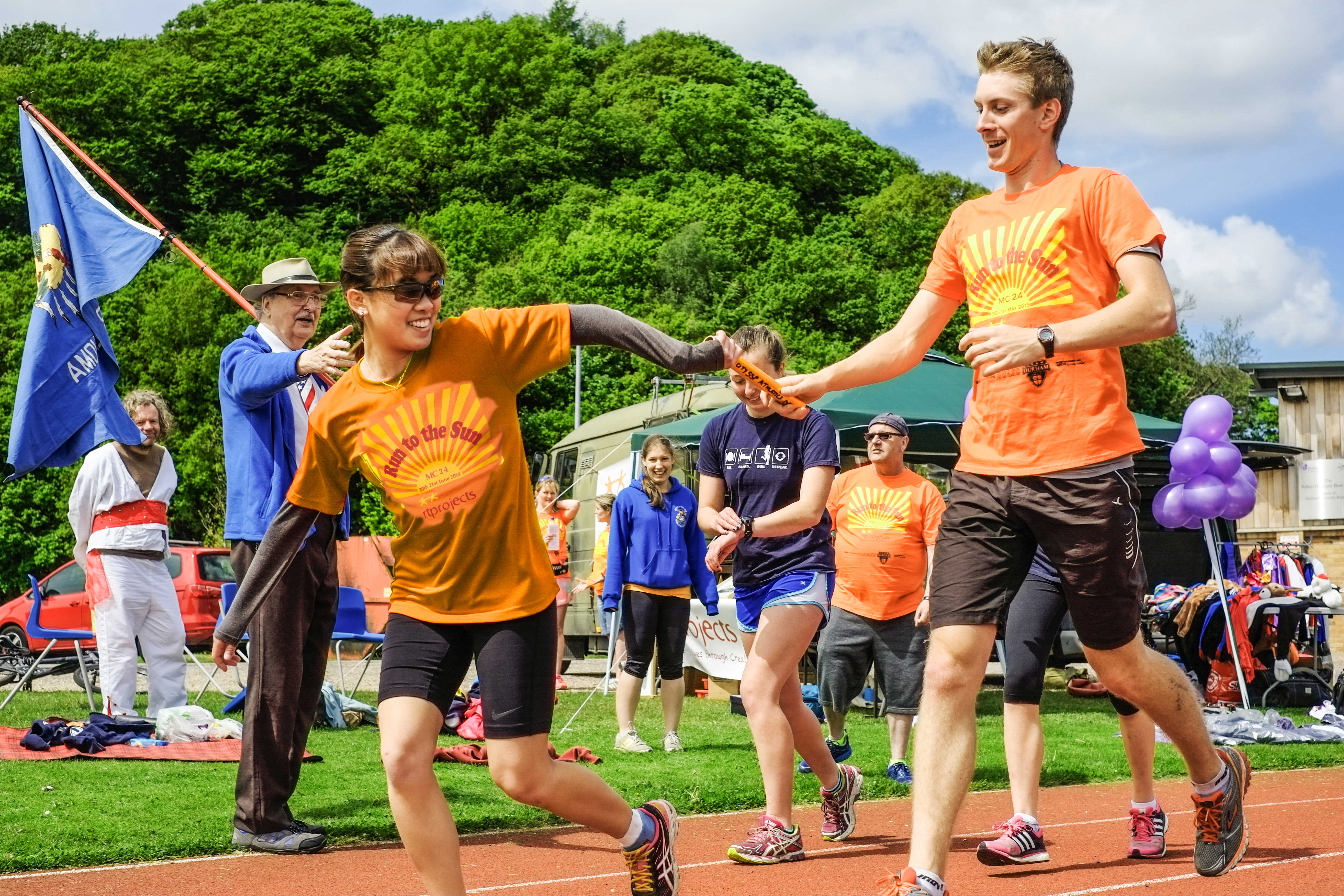 Two runners swapping the baton at run to the sun